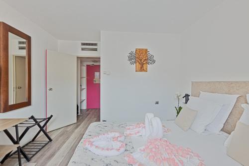 a white bedroom with a bed and a table at Hôtel Provence in Draguignan