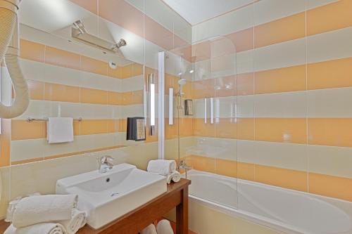 a bathroom with a sink and a tub at Hôtel Provence in Draguignan
