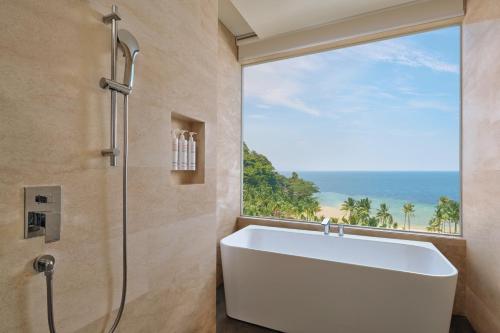 uma banheira na casa de banho com uma grande janela em Lampung Marriott Resort & Spa em Lampung