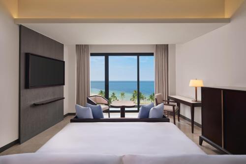 LampungにあるLampung Marriott Resort & Spaのベッド付きのホテルルームで、海の景色を望めます。