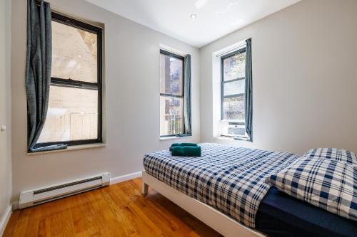 a bedroom with a bed and two windows at Park Side Living, City Style in New York