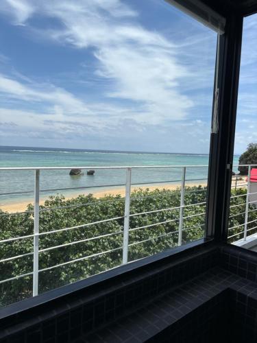 uma vista para a praia a partir de um quarto com uma janela em CASA DUMAI OceanVilla NAKIJIN em Nakijin