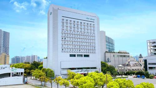 a tall white building with trees in front of it at Hotel Springs Makuhari in Chiba