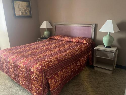 een slaapkamer met een bed en twee nachtkastjes met lampen bij Hotel Pacific Garden in Gardena