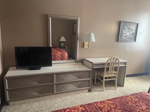 een hotelkamer met een televisie en een bureau met een bed bij Hotel Pacific Garden in Gardena