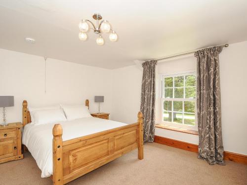 a bedroom with a bed and a window at Lee Barton Farmhouse in Bude