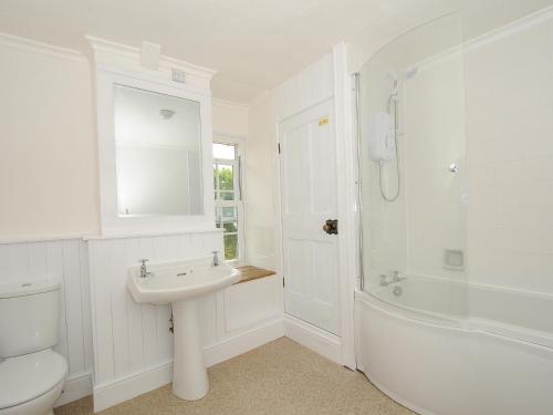 a white bathroom with a sink and a tub and a toilet at Lee Barton Farmhouse in Bude