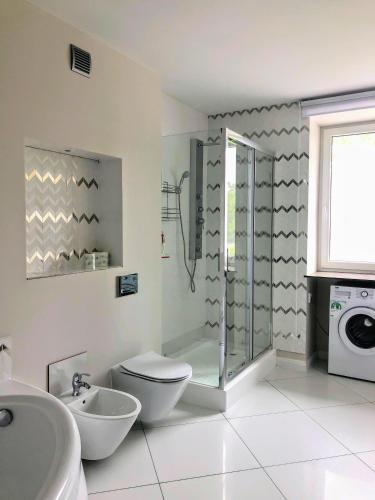 a bathroom with a shower and a toilet and a washing machine at Apartament w willi Karczyn - noclegi dla miłośników natury i spokoju in Karczyn