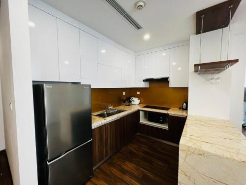 a kitchen with white cabinets and a stainless steel refrigerator at Nesta - The Grand Hao Nam in Hanoi