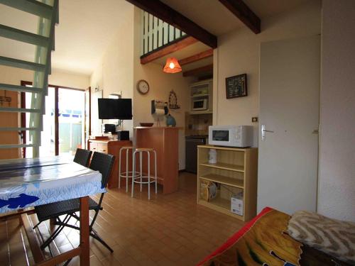 Il comprend une cuisine et un salon avec une table et un four micro-ondes. dans l'établissement Maison aux Mathes : Piscine, Tennis, Proche Plage et Commerces - FR-1-705-50, aux Mathes