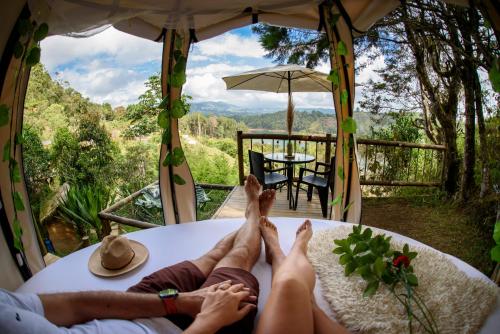 a couple laying on a table with their feet up in a chair at Levit Glamping - Hotel Guatapé Peñol in Guatapé