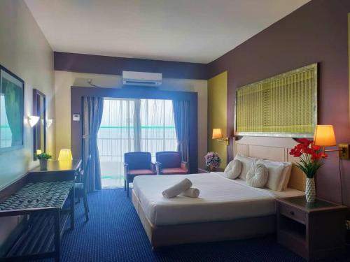 a hotel room with a bed and a table and chairs at Jazz Rainbow Paradise beachfront Peanag in Tanjung Bungah
