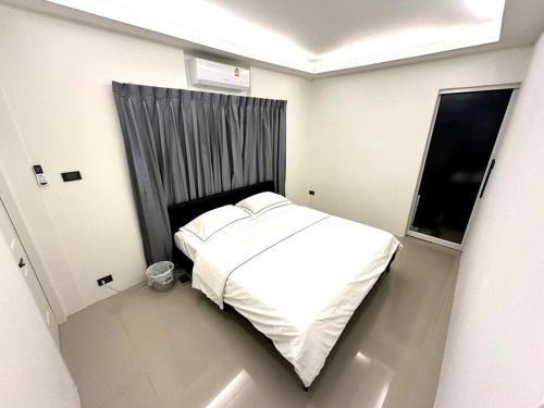 a small bedroom with a white bed and a window at Cape House in Ban Bang Kaeo