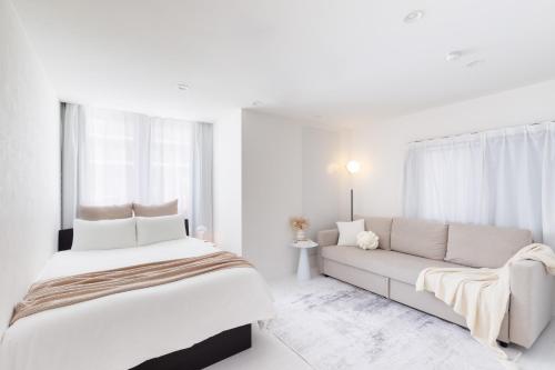 a white bedroom with a large bed and a couch at City Hotel Namba Prime in Osaka