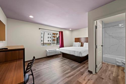 a hotel room with a bed and a bathroom at Hyland Inn Long Beach in Long Beach