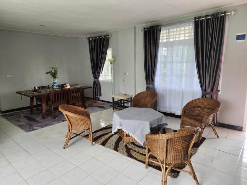Porlak Hebron Family Homestay في Siborongborong: غرفة معيشة مع طاولة وكراسي