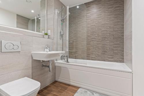 een badkamer met een bad, een wastafel en een toilet bij Luxury Birmingham city centre apartment in Birmingham