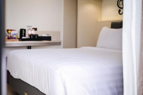 a bedroom with a white bed and a table at Kesuma Front One Boutique Palembang in Palembang