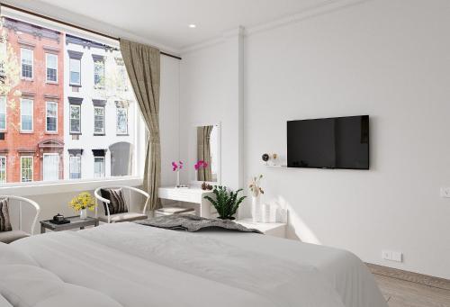 a white bedroom with a bed and a tv on a wall at Walhalla Hotel Saigon in Ho Chi Minh City