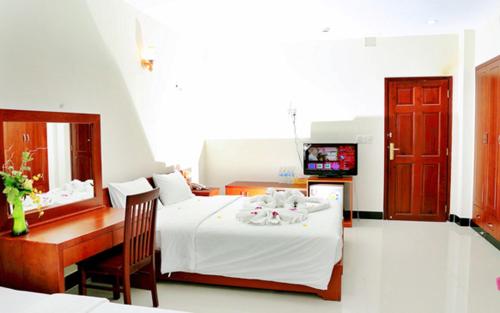 een slaapkamer met een bed, een bureau en een televisie bij Ben Dua in Chợ Giồng Trôm