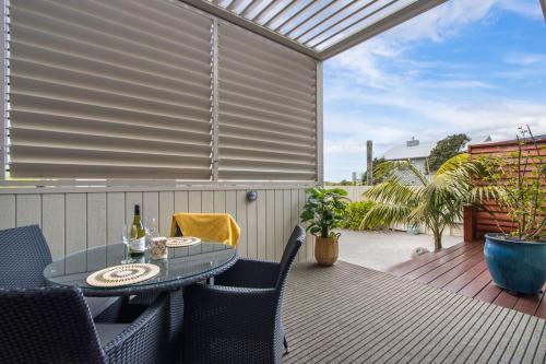 a patio with a table and chairs on a deck at Te Mahana Coastal Retreat in Waihi Beach
