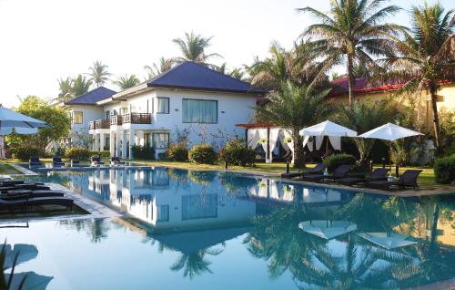 a pool with chairs and umbrellas in front of a house at Puerto Del Sol Beach Resort and Hotel Club Bolinao Pangasinan in Bolinao