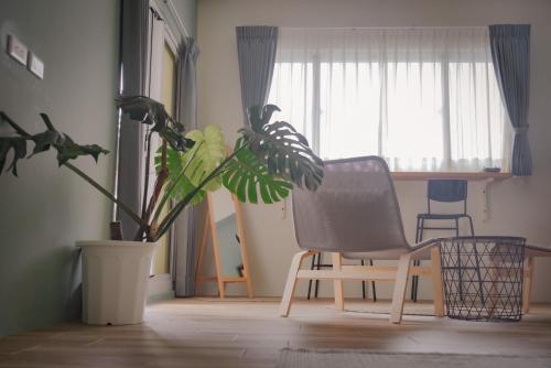 einen Stuhl und eine Pflanze in einem Zimmer mit Fenster in der Unterkunft 富士A’tolan in Fushan