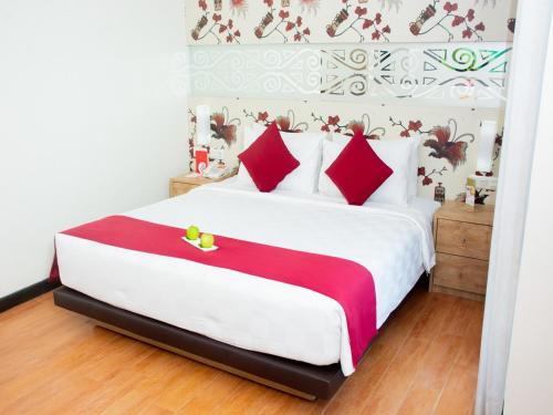ein Schlafzimmer mit einem großen weißen Bett mit roten Kissen in der Unterkunft @Hom Premiere by Horison Abepura in Abepura