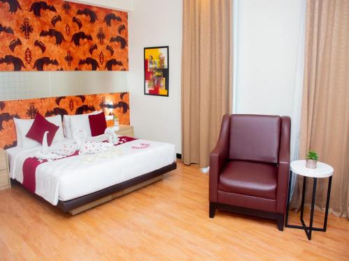 1 dormitorio con 1 cama y 1 silla roja en @Hom Premiere by Horison Abepura en Abepura