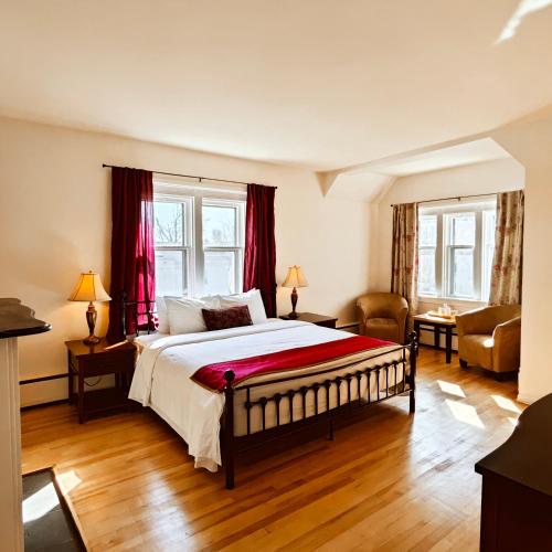 a bedroom with a large bed with red curtains at Andy's Blue House in Charlottetown