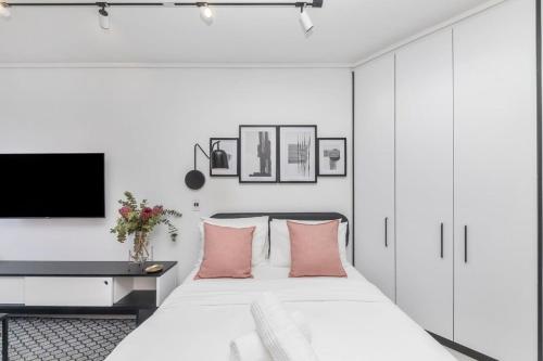 a white bedroom with a large bed with pink pillows at 508 The Flamingo *Central* *Netflix* Aircon* in Cape Town