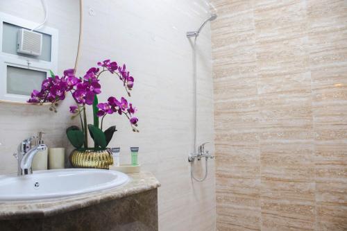 a bathroom with a sink and a shower with purple flowers at Amazing Studio Apartments Zc in Abu Dhabi