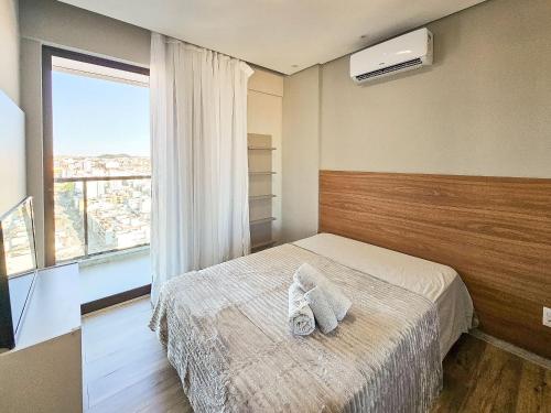 a bedroom with a bed and a large window at Nosso Apê Cascatinha: Garagem | Ar-condicionado | Piscina | Sauna NA1304 in Juiz de Fora