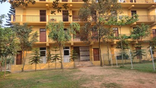 un bâtiment jaune avec des arbres devant lui dans l'établissement Vosu Homestay, à Dimāpur