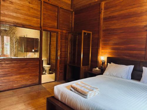 een slaapkamer met houten wanden en een bed met twee handdoeken erop bij Uli Wood Villa, Jimbaran BALI - near GWK in Jimbaran