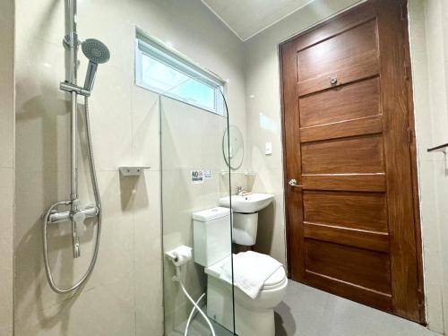 a bathroom with a shower and a toilet and a glass door at Sunburn Suites and Rooftop Bar in Coron