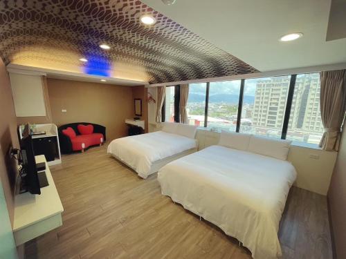 a hotel room with two beds and a red chair at 幸福星空時尚旅館 in Luodong