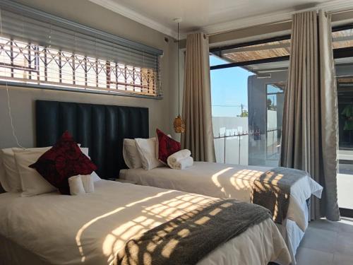 two beds in a bedroom with a view of the ocean at The Space Guesthouse Mondlo in Mondlo