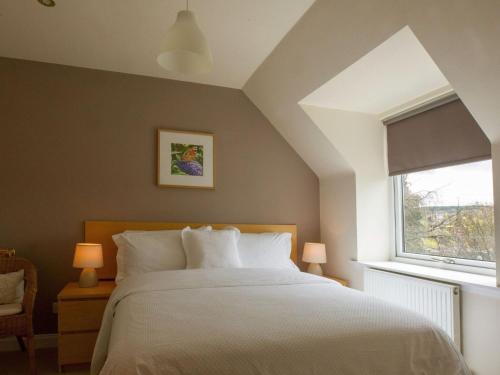 1 dormitorio con cama blanca y ventana en Attractive cottage in garden grounds en Jedburgh