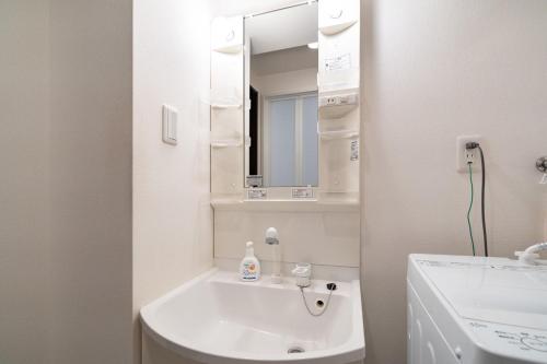 a white bathroom with a sink and a mirror at Best Residence Kujo in Osaka