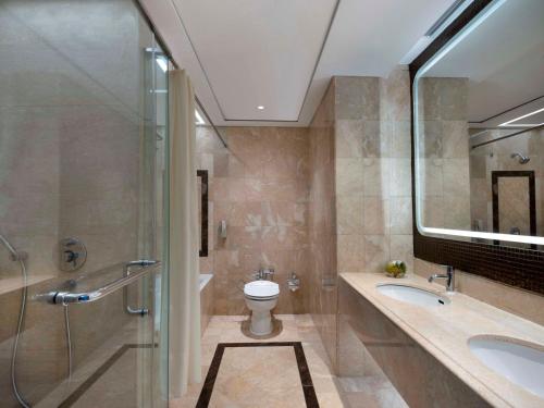a bathroom with a toilet and a shower and a sink at Hotel Ciputra Jakarta managed by Swiss-Belhotel International in Jakarta