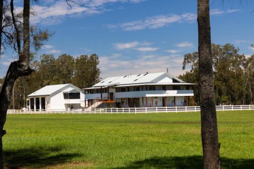 a white building with a white fence in a field at Neat Acres Farmhouse in Darawank
