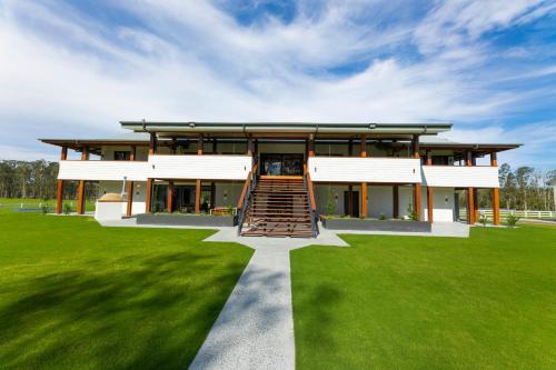 a large building with a staircase in a grass field at Neat Acres Farmhouse in Darawank