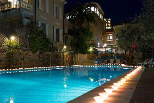 een zwembad 's nachts met verlichting bij Hotel Villa Igea in Diano Marina