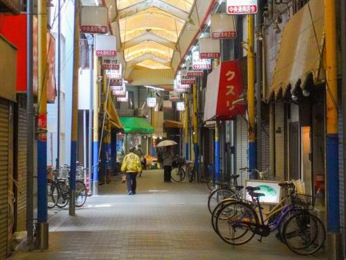 a person walking down an alley with bikes on a street at 鯉 in Osaka