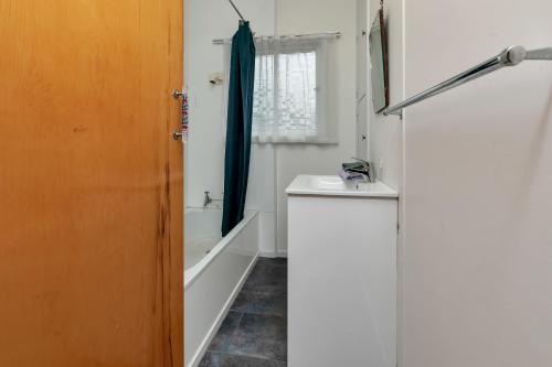 a bathroom with a sink and a toilet and a shower at Sandy Cottage - Tokerau Beach Holiday Home in Kaitaia