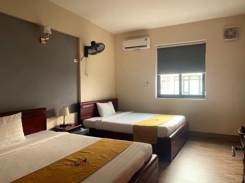 a hotel room with two beds and a window at Khách sạn HOÀ BÌNH QUẢNG TRỊ in Ðông Hà