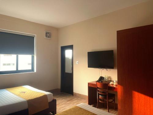 a hotel room with a bed and a desk and a television at Khách sạn HOÀ BÌNH QUẢNG TRỊ in Ðông Hà