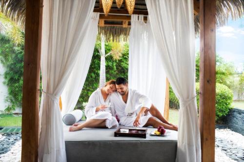 a man and woman sitting on a bed in a room at Nickelodeon Hotels & Resorts Punta Cana - Gourmet All Inclusive by Karisma in Punta Cana