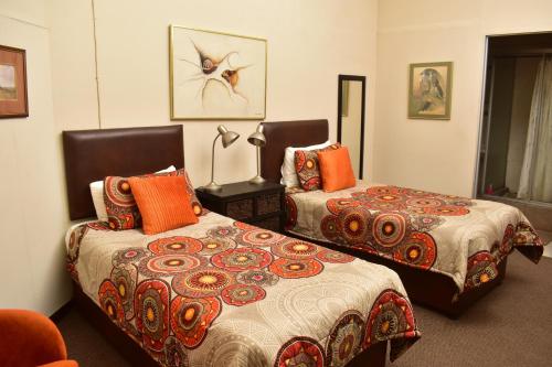 sypialnia z 2 łóżkami i pomarańczowymi poduszkami w obiekcie kestell Hotel w mieście Kestell